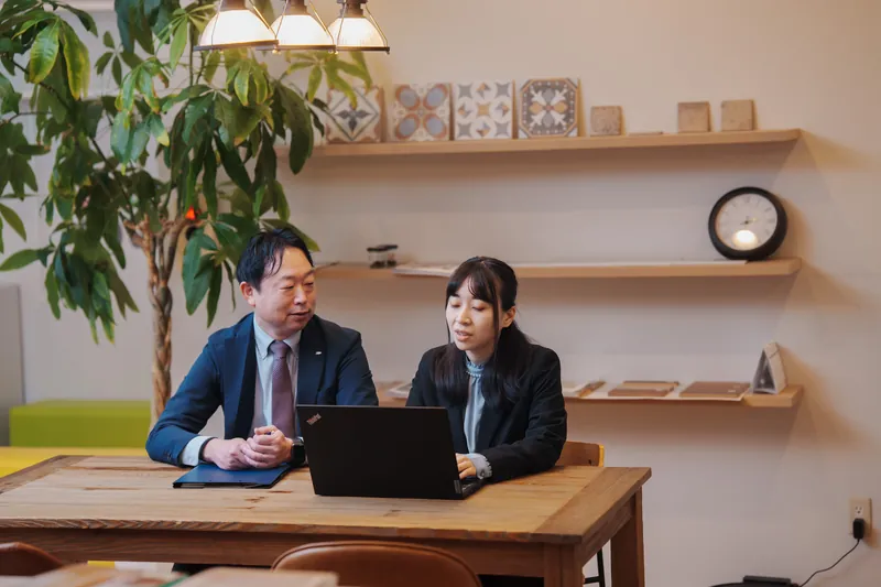 観葉植物のあるオフィスで打ち合わせをするスタッフ